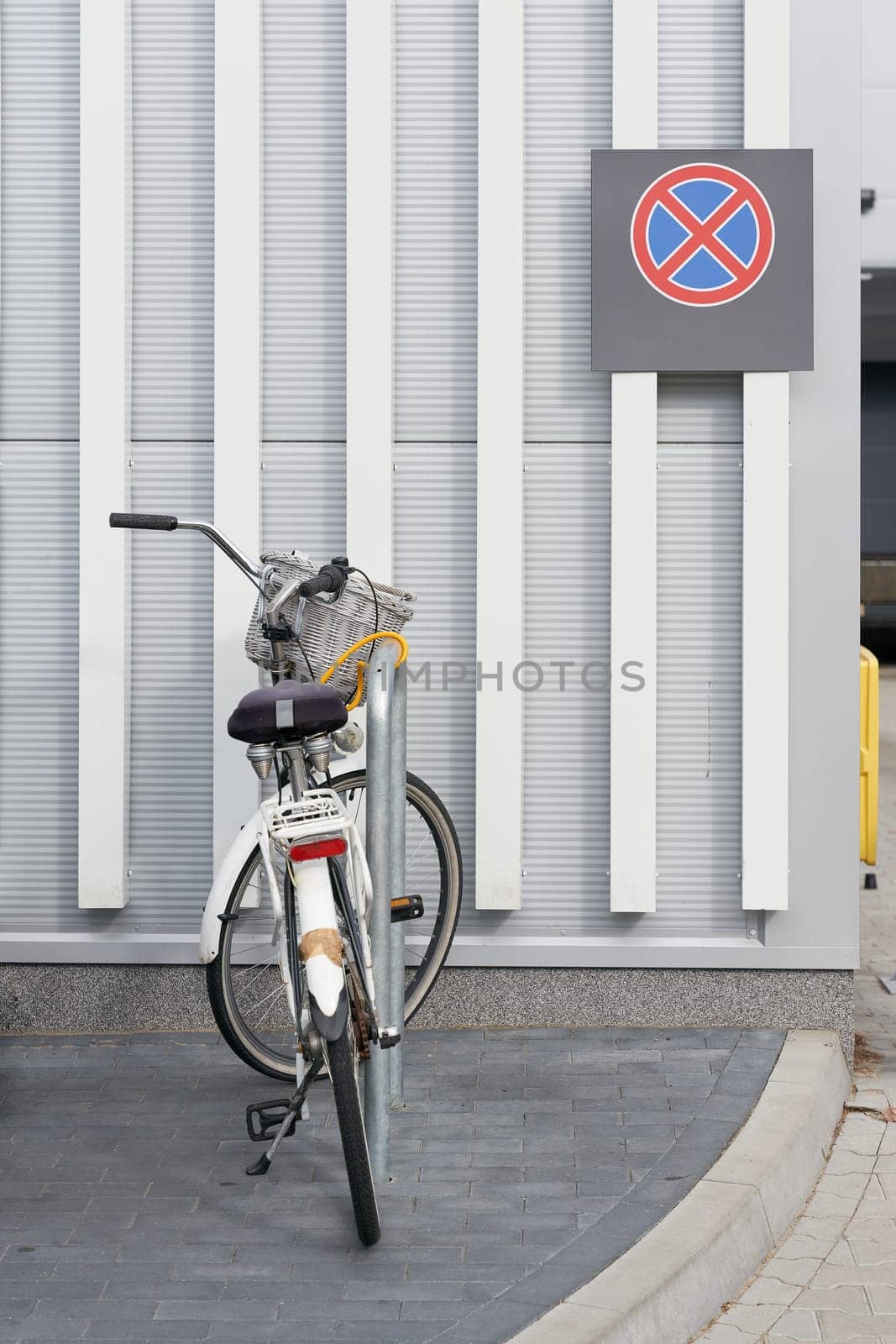 parked bicycle at a supermarket, behind it a no stopping sign on the wall