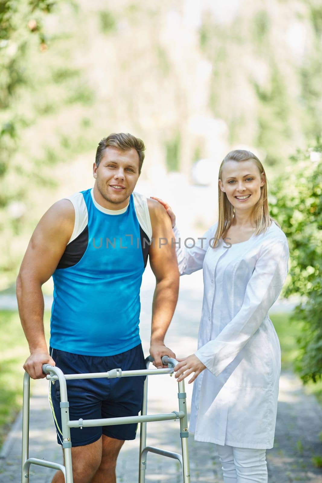 Young clinician and her patient looking at camera during walk in park