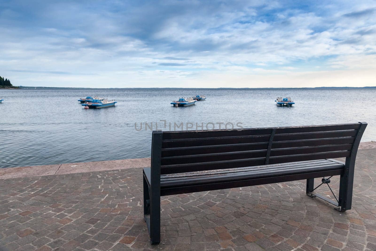 empty bench overlooking Lake Garda and boats