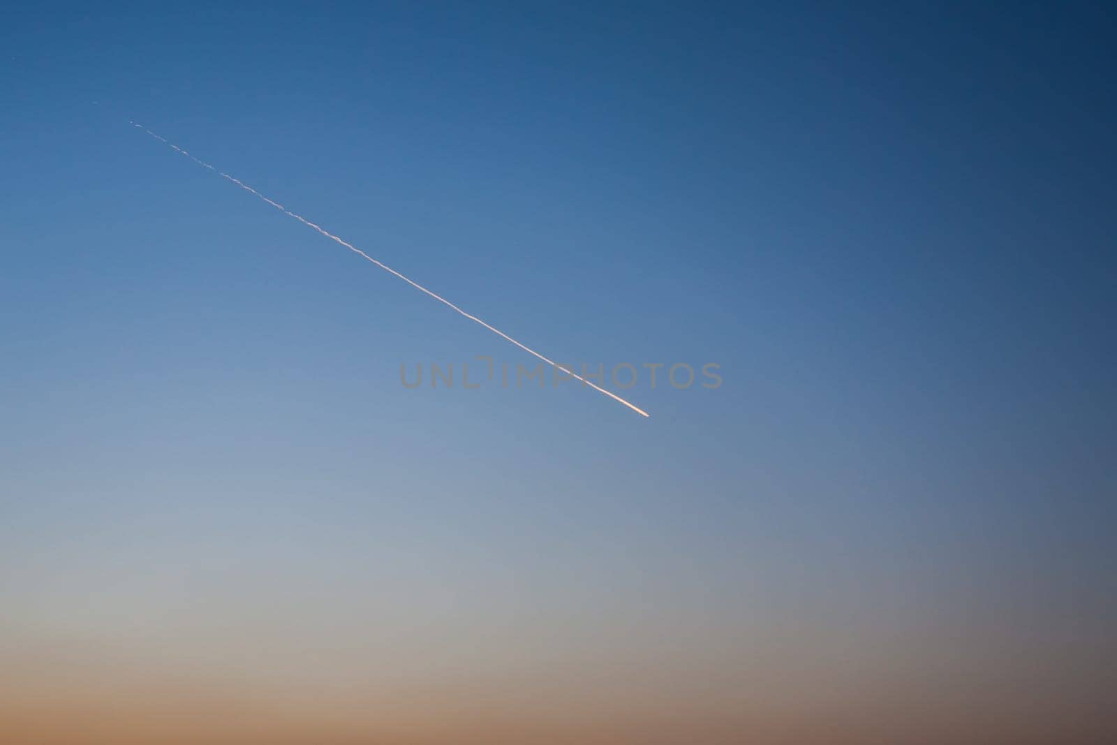 The trace of the plane in the sky, in the clear evening sky remained the trace of the flying plane in the distance