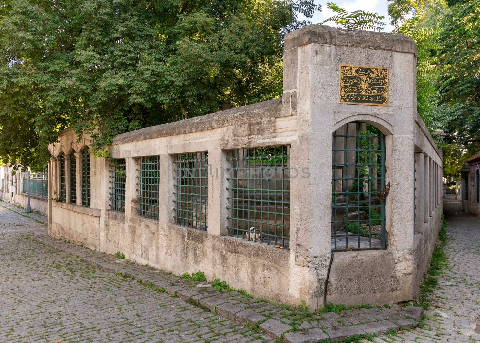 Cobblestone alley at Eyup Sultan Cemetery, with stone fence built of stone bricks and wrought iron windows, located near Eyup Sultan Mosque at Eyup district, Golden Horn, Istanbul, Turkey