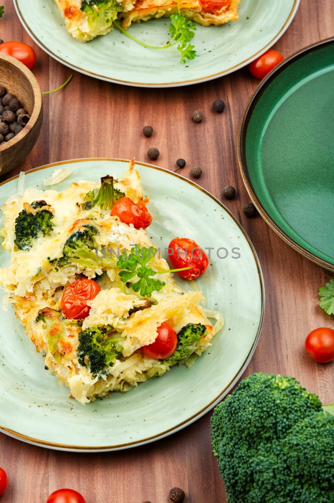 Appetizing potato casserole with broccoli and tomatoes on a plate.