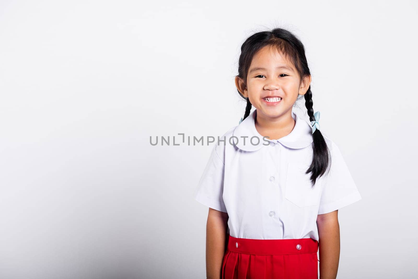 Asian adorable toddler smiling happy wearing student thai uniform red skirt standing in studio shot isolated on white background, Portrait little children girl preschool, Happy child Back to school