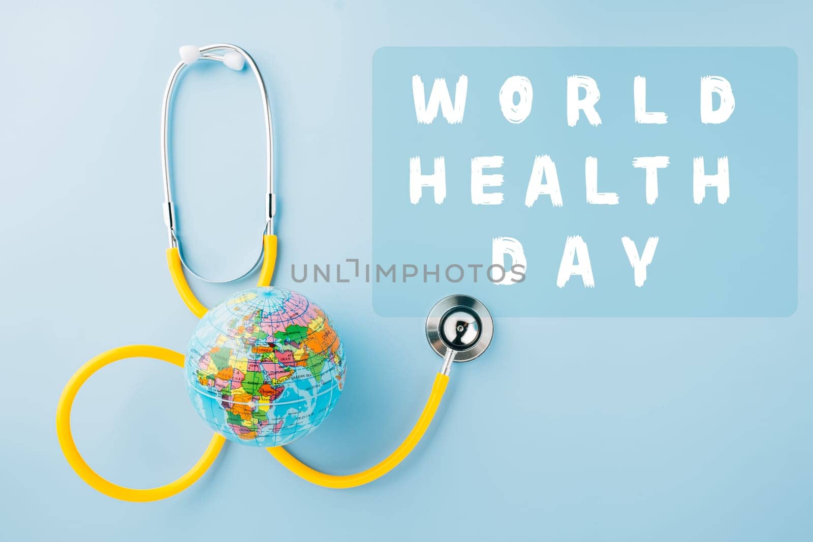 World Health Day Concept. Top view yellow doctor stethoscope and world globe isolated on pastel blue background with copy space, Save world day, Environment Green Earth, Health care and medical