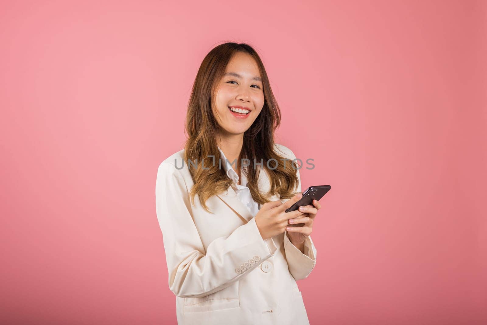 Female surprised and sms chatting internet online on smartphone studio shot isolated on pink background, Happy Asian portrait beautiful cute young woman teen smiling excited hold smart mobile phone