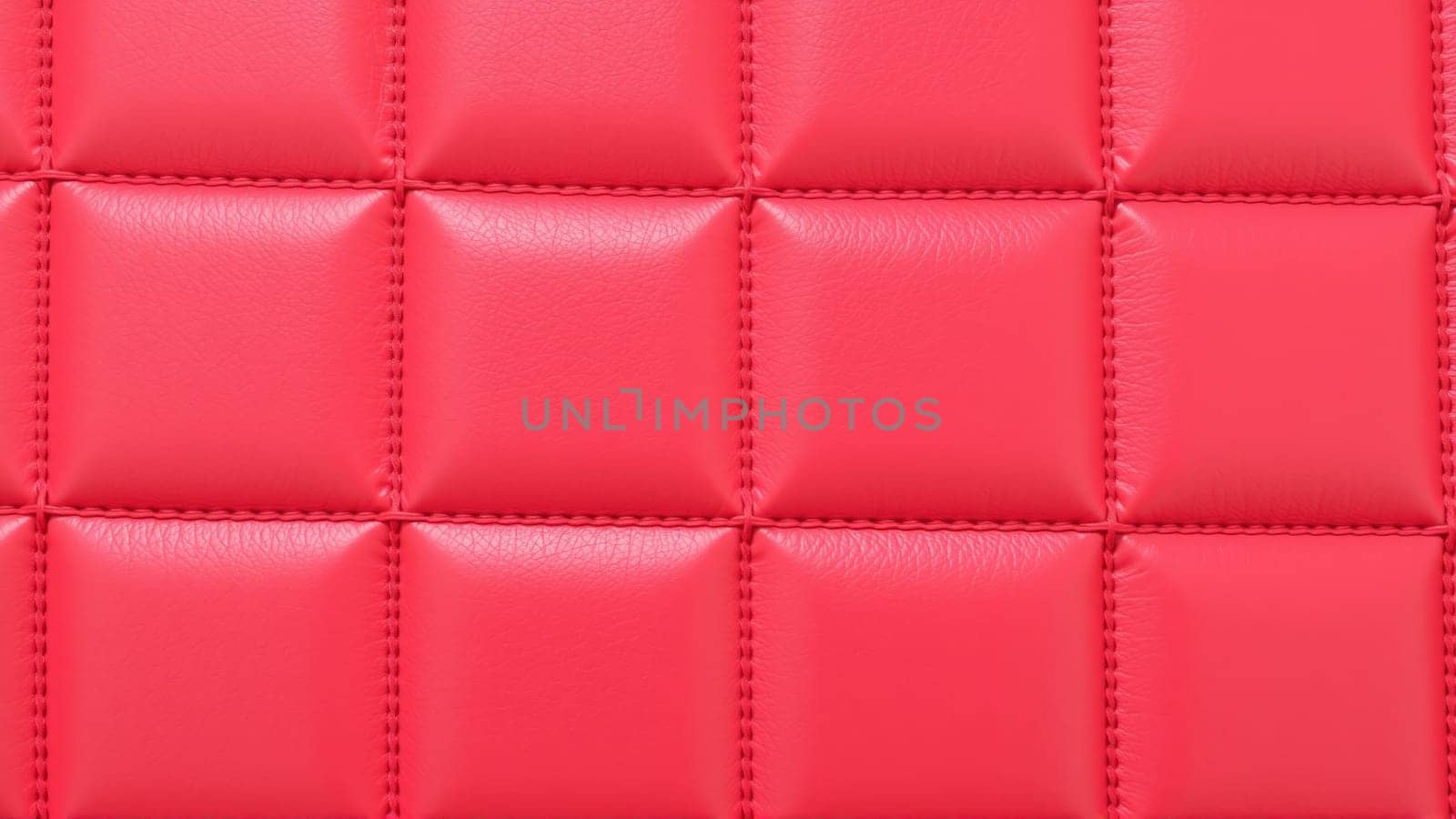 The surface texture of artificial leather in red, stitched in the form of rhombuses, squares, rectangles. Quilted eco-leather. High quality photo