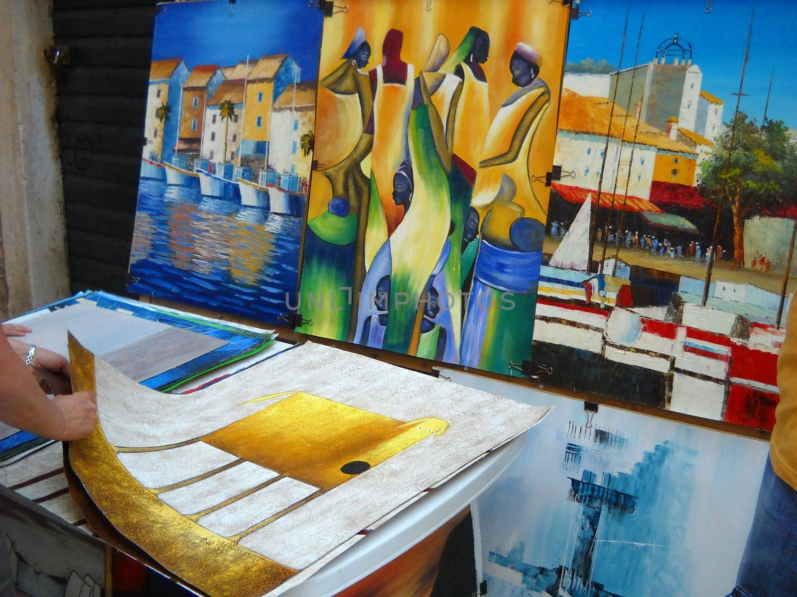 Dubrovnik, Croatia, August 5 2010 People buy paintings by street artists. Sale of souvenirs and creative works. Human hands shift and touch colorful drawings. Tourist attractions of the Adriatic coast