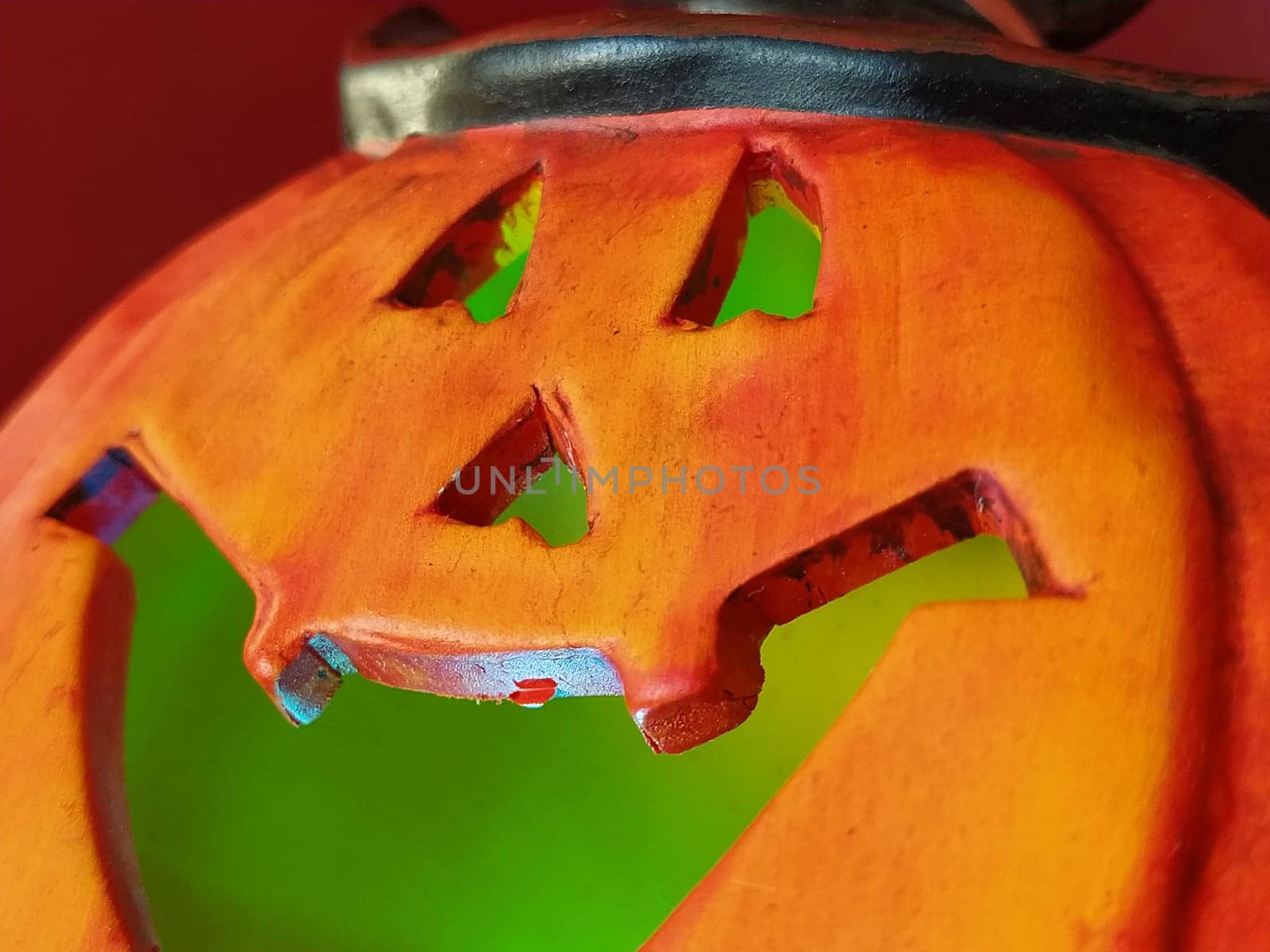 Bright orange Halloween pumpkin. Cut holes for mouth, nose and eyes. Green scary glow from the inside of the pumpkin. Close-up. The sinister laugh of the monster. Blurring the edges of the image.
