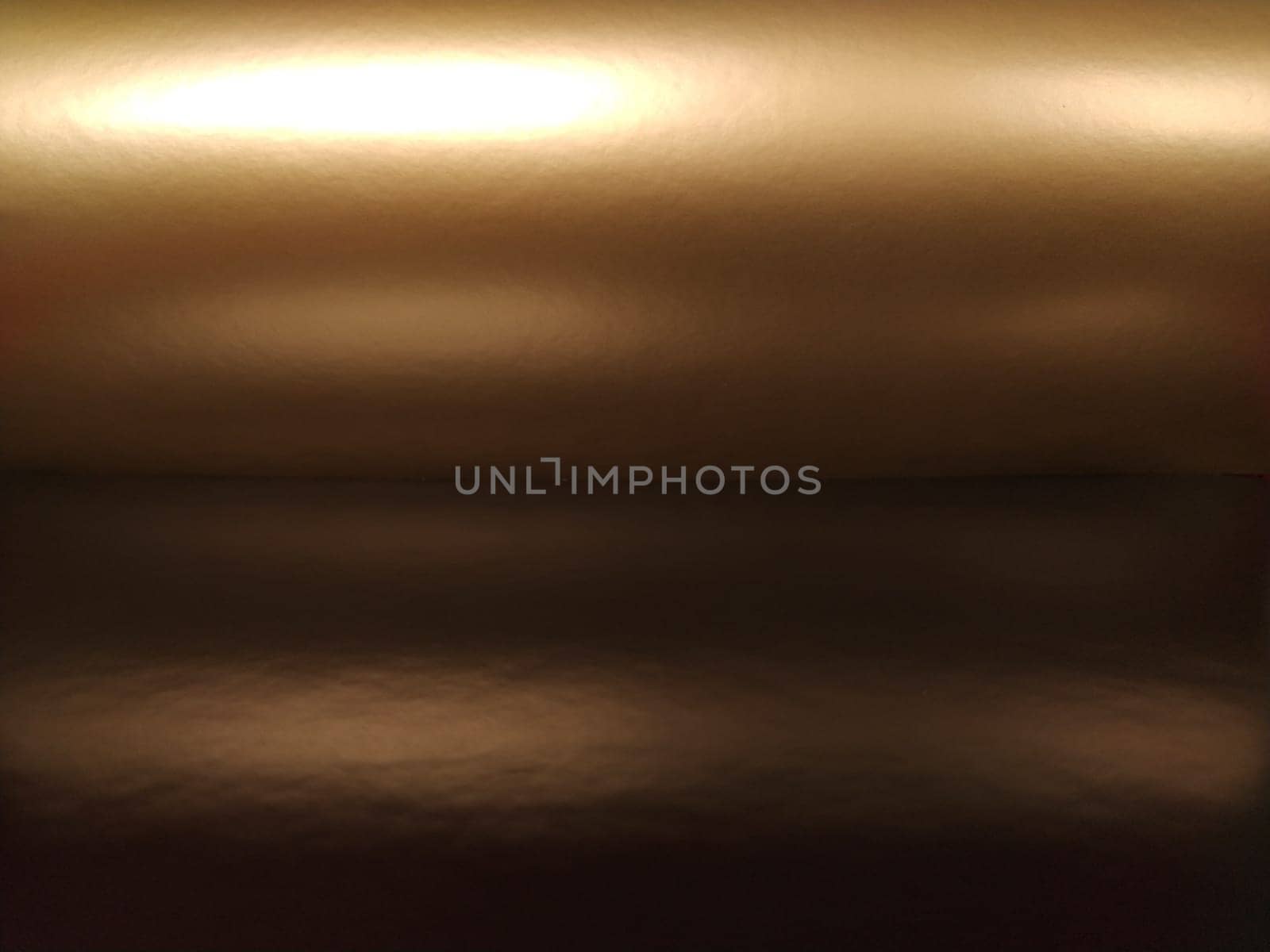 Gradient on a brown background. Horizontally folded shiny paper or foil with overflow and glare. Soft brown and beige color. Mysterious radiance. Northern Lights. Luxury fabric. Metallic gold glitter.