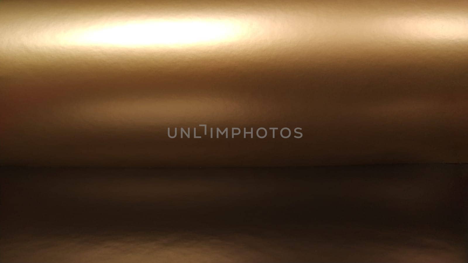 Gradient on a brown background. Horizontally folded shiny paper or foil with overflow and glare. Soft brown and beige color. Mysterious radiance. Northern Lights. Luxury fabric. Metallic gold glitter. Banner