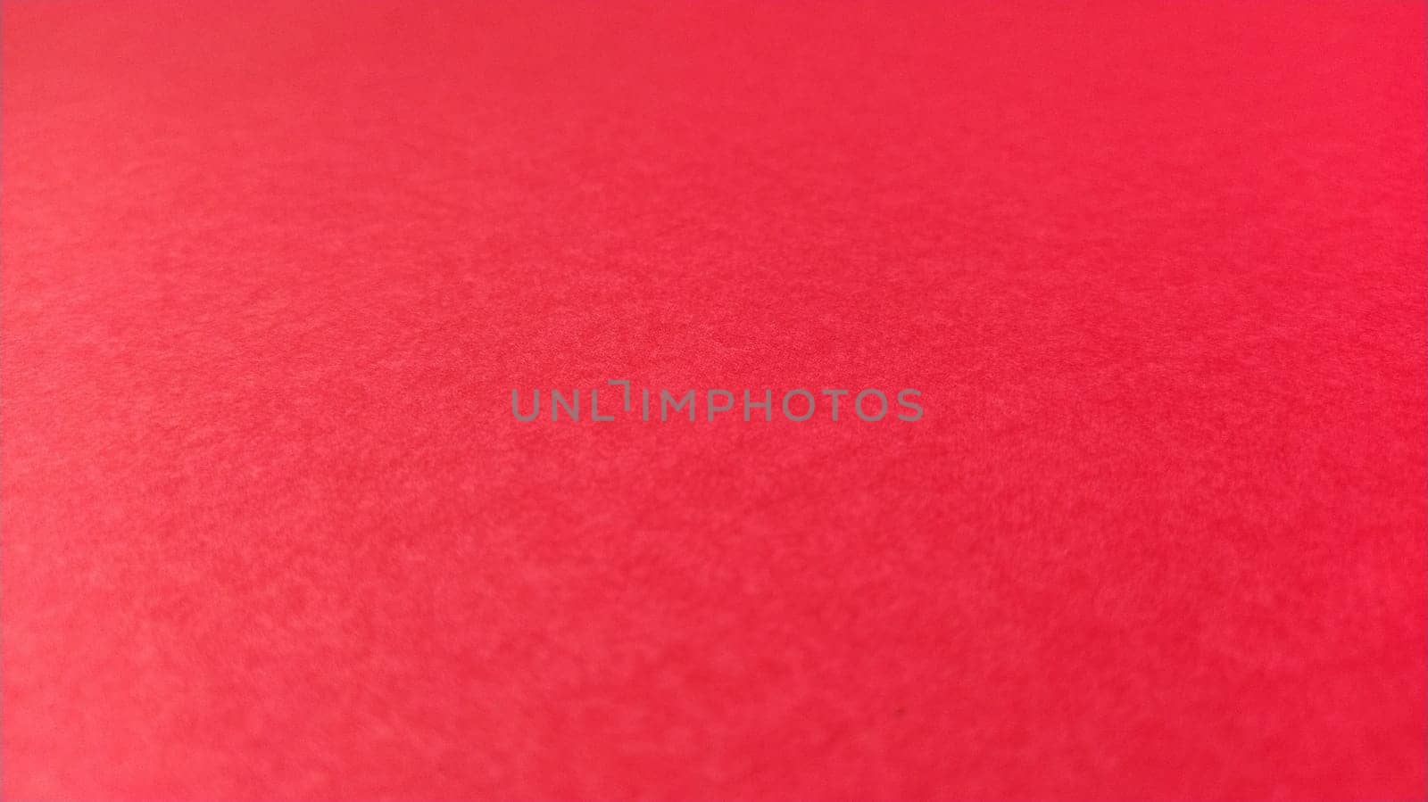 Beautiful red bright background. Scarlet color. A rough sheet of colored paper with natural light. Fragment of a sheet of colored paper with a thin fleecy surface