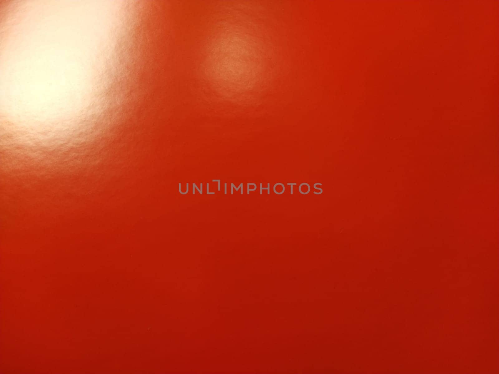 Beautiful bright red background. Closeup sheet of shiny reflecting incident light paper. Pure fun color. Intense shade of red, close to scarlet or blood color with high reflectivity