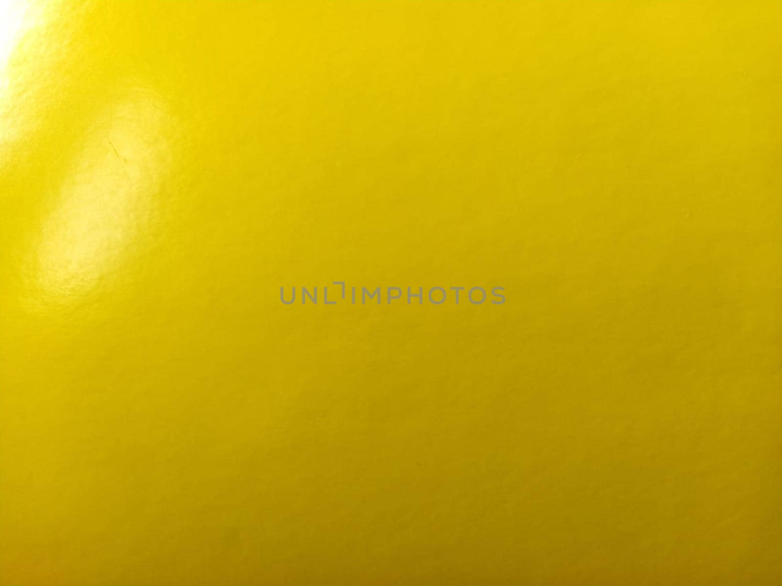 Beautiful bright yellow background. Close-up sheet of shiny reflective incident light paper. Pure fun color. Intense shade of yellow, close to gold or sunny with high reflectivity