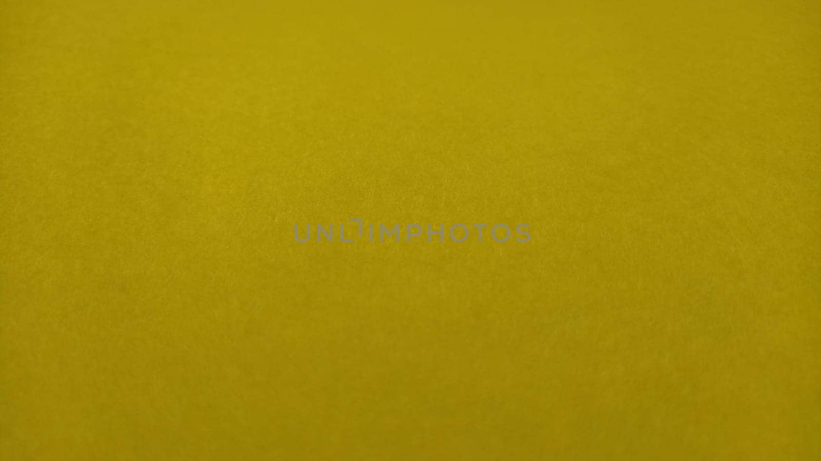 The paper or fabric is bright yellow. Close-up. Lightly folded sheet. Light gradient and accentuated rough surface texture. Background or product sample. Sunny cheerful yellow. Copy space.