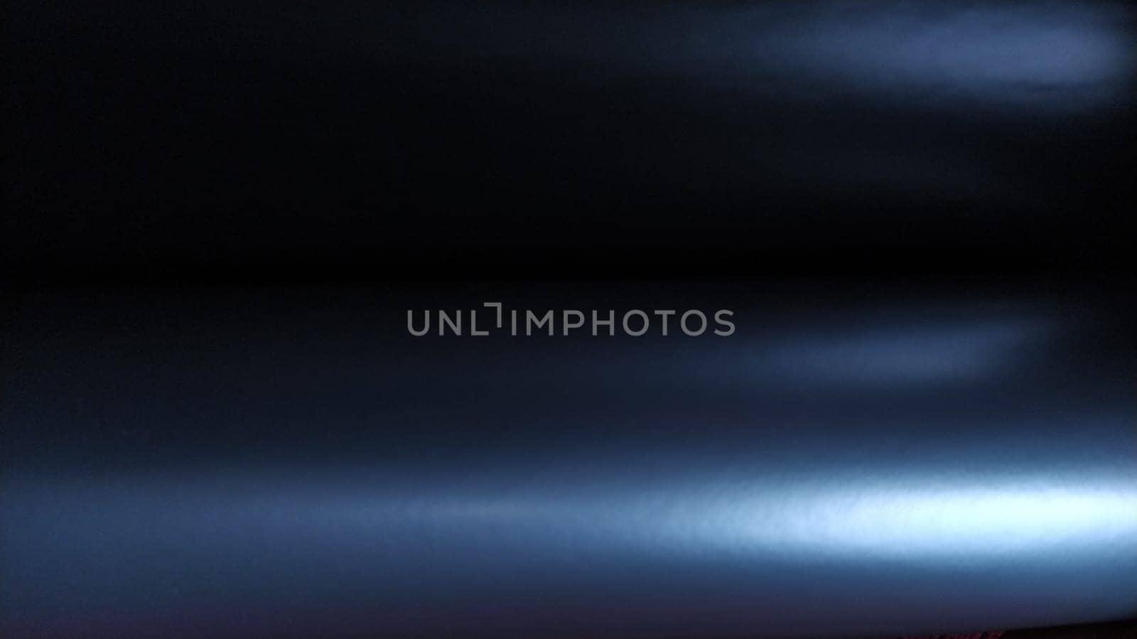 Gradient on a blue-violet background. Horizontally folded shiny paper or foil with overflow and highlights. Mysterious radiance. Luxurious fabric. Metallic cold shine