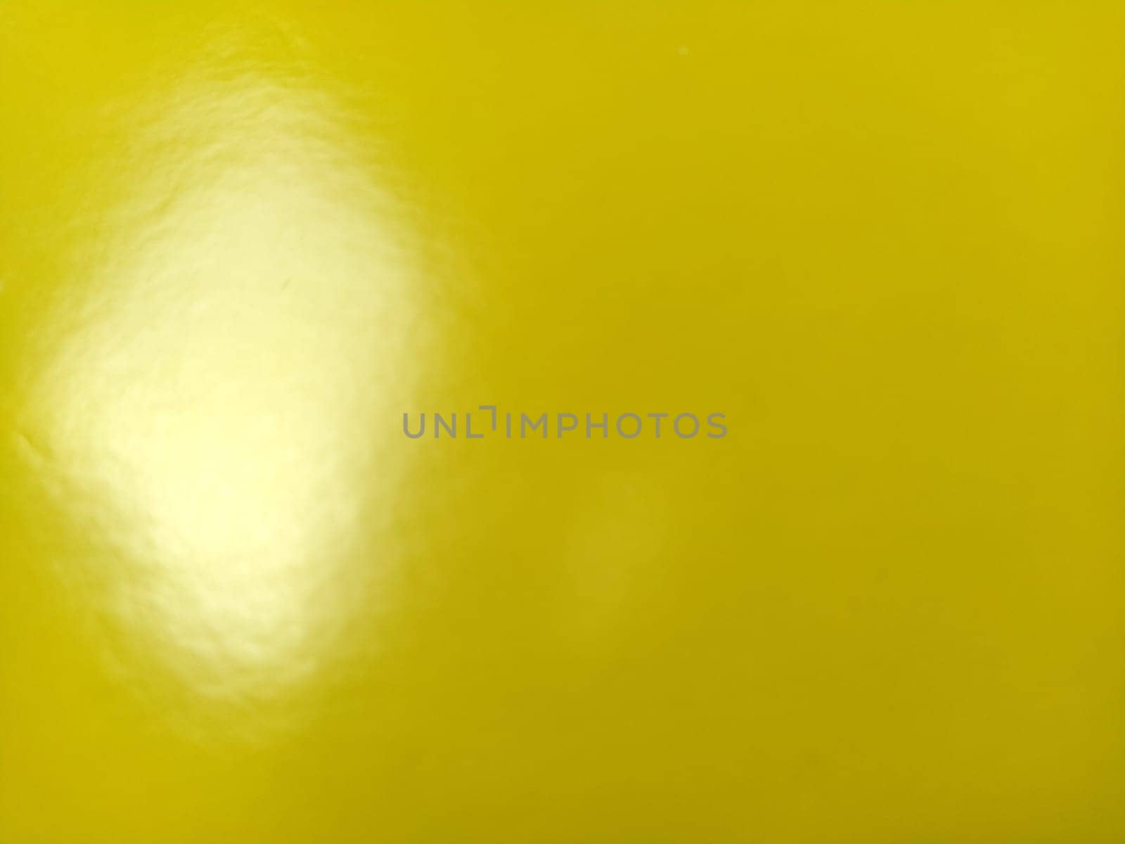 Beautiful bright yellow background. Close-up sheet of shiny reflective incident light paper. Pure fun color. Intense shade of yellow, close to gold or sunny with high reflectivity.