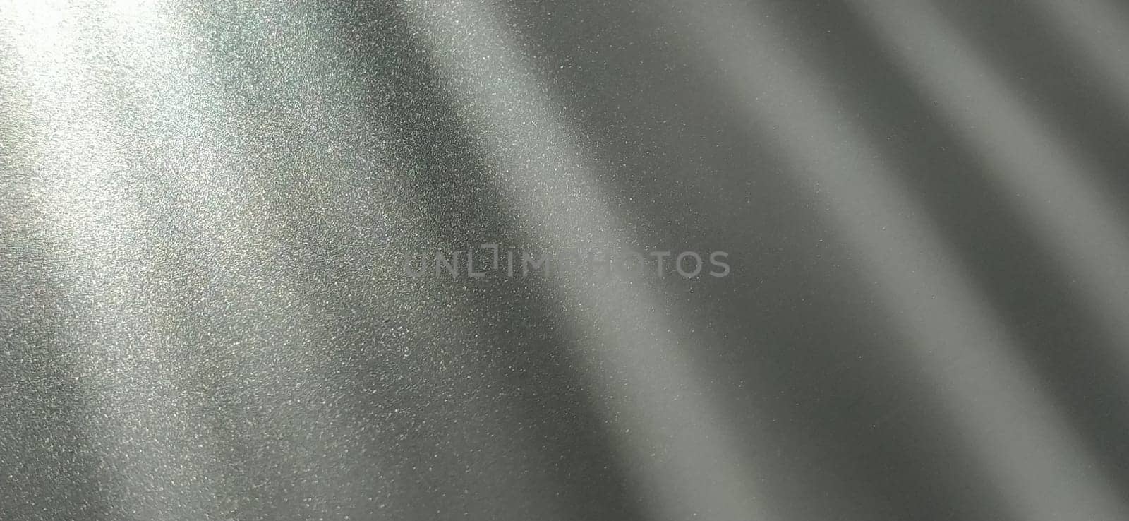 Gray striped background with oblique light effect. Play of light and shadow. Light rays. Gray and silver shades with white dots and shining stars. Diagonal lines from left to right.
