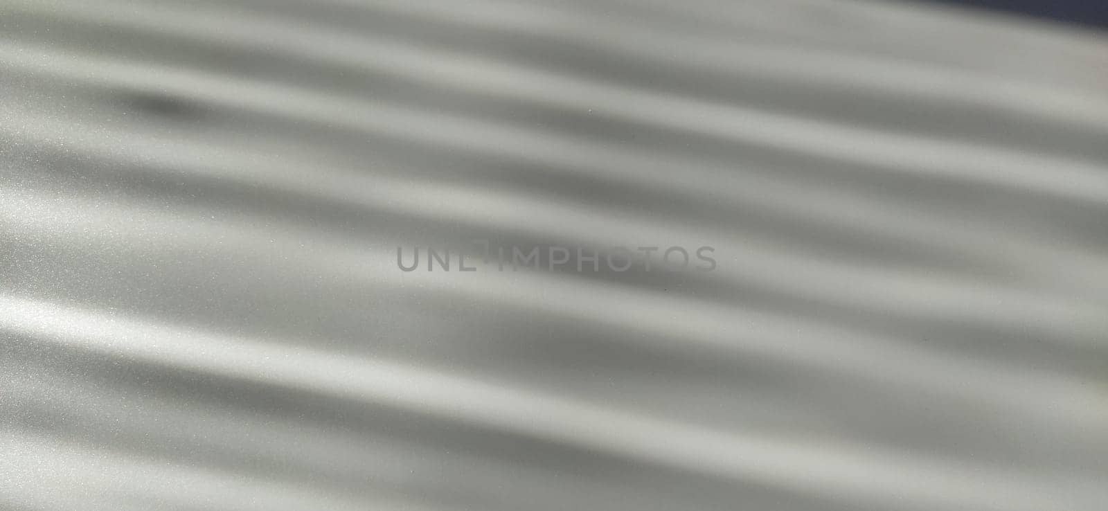 Gray striped background with oblique light effect. Play of light and shadow. Light rays. Gray and silver shades with white dots and shining stars. Diagonal lines from left to right.