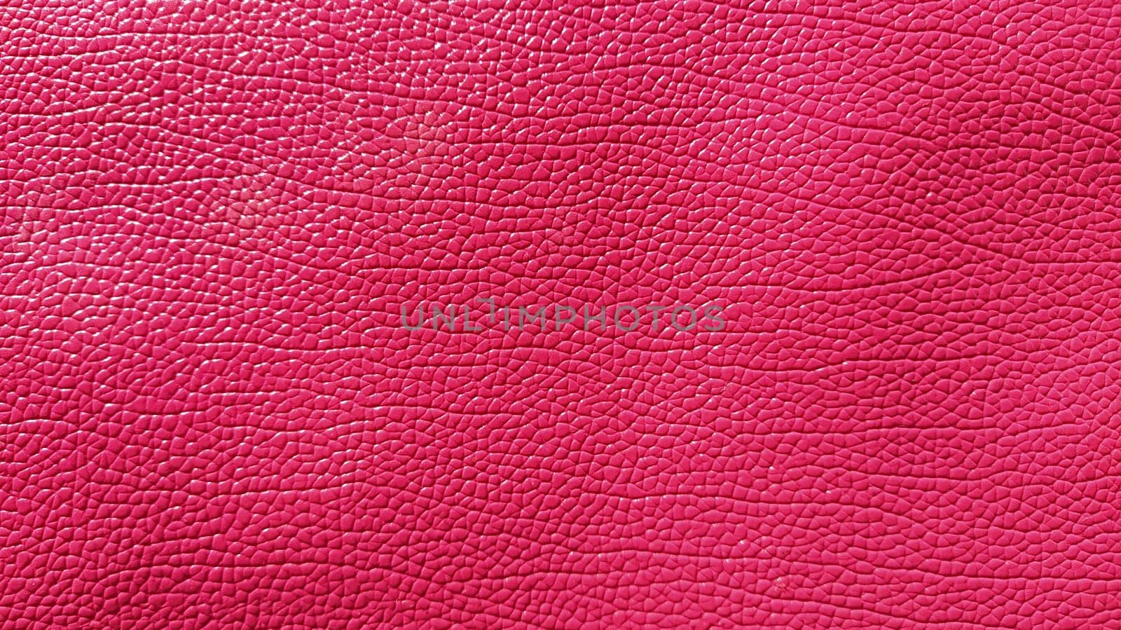 Close-up detail of pink leather. Bright fuchsia background. Skin texture. Artificial leather or imitation.
