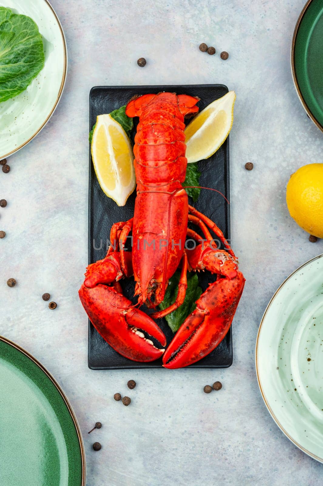 Boiled lobster with greens and lemon on a plate. Seafood.