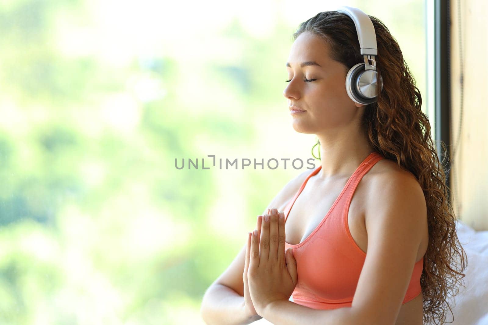 Happy woman meditating with headphone at home