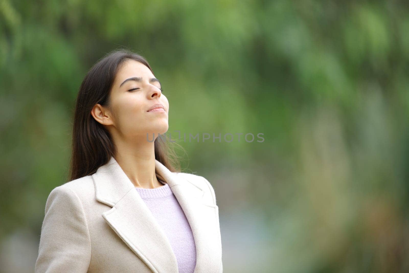 Woman in winter breathing fresh air in nature in a park
