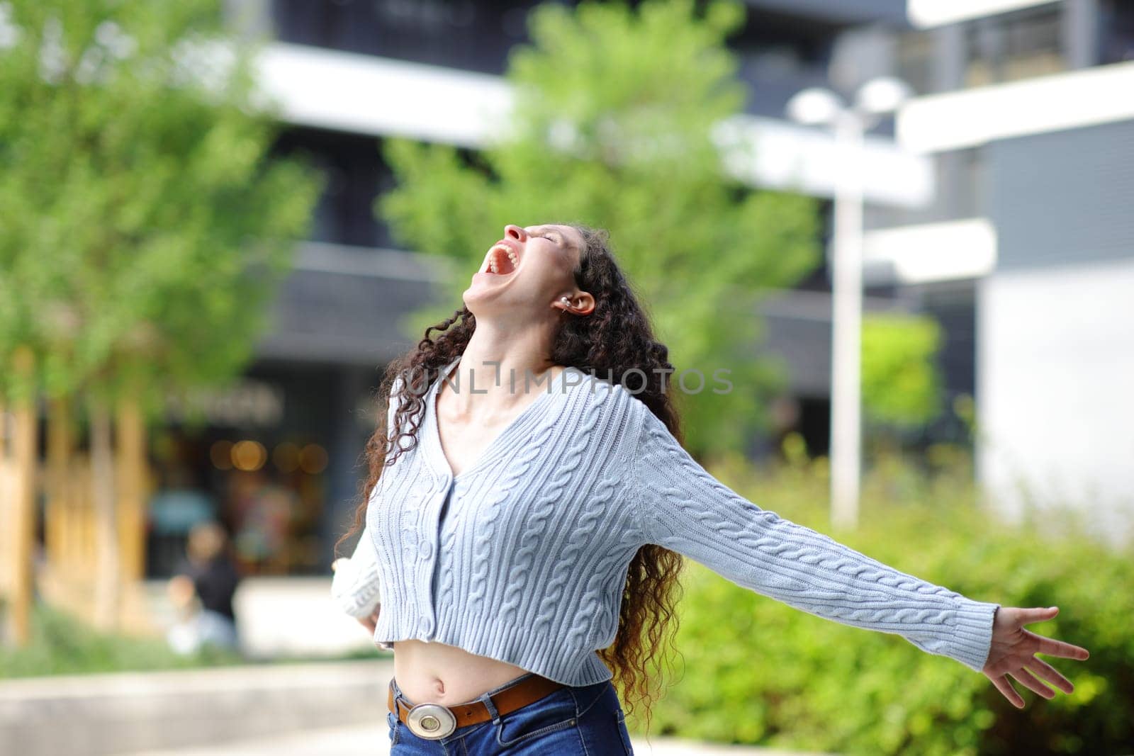 Excited woman in the street outstretching arms screaming
