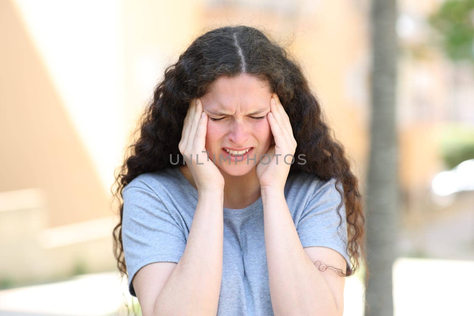 Woman suffering migraine complaining in the street