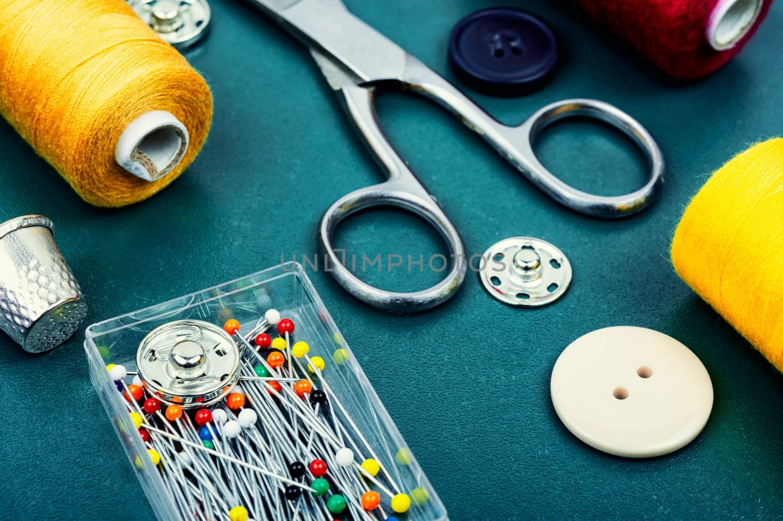 Home sewing kit, scissors, color threads, needles and buttons. Needlework concept