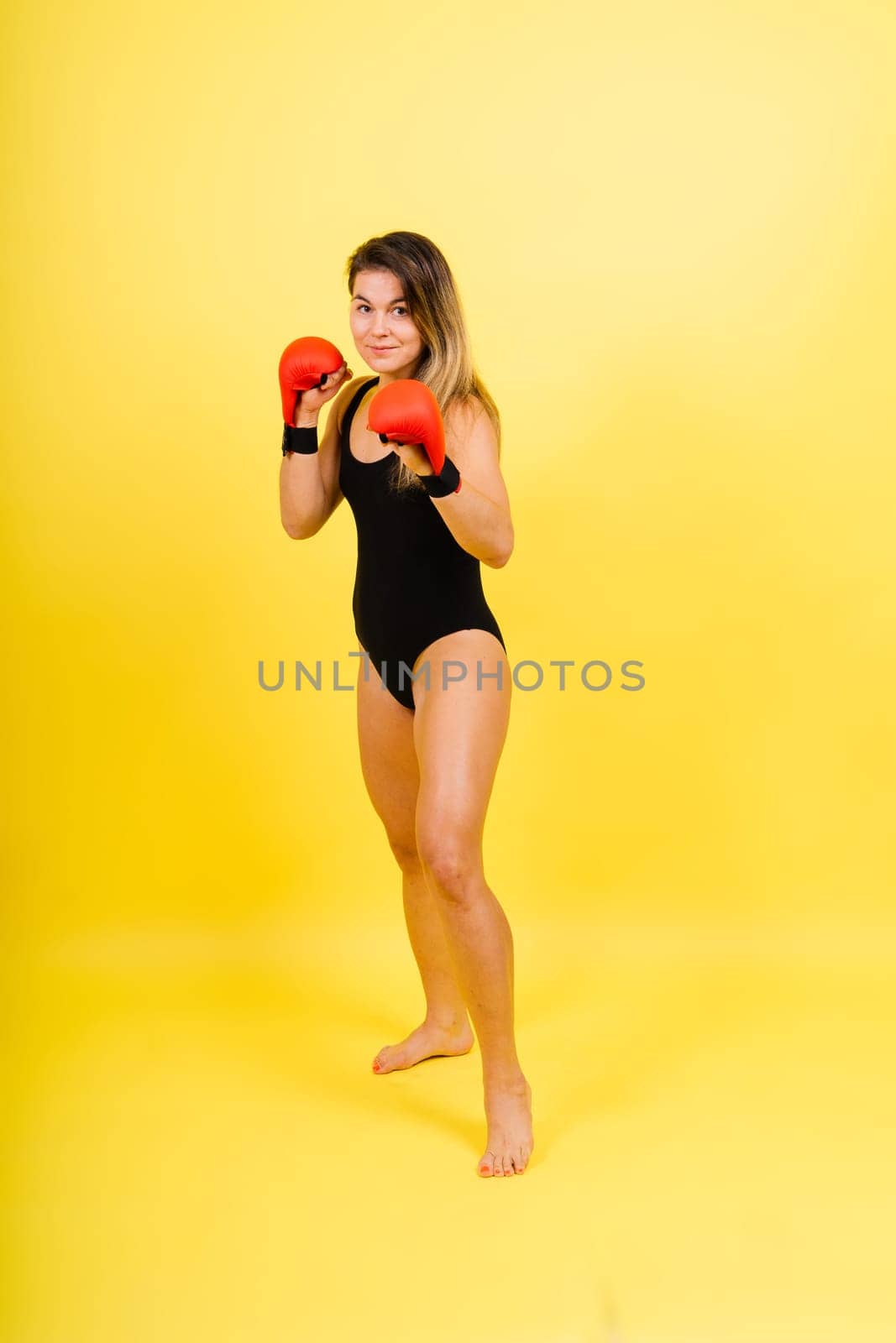 Cool female fighter in boxing bandages trains in a studio. Mixed martial arts.