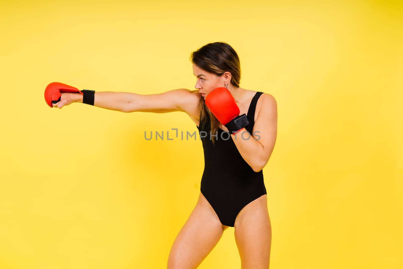 Cool female fighter in boxing bandages trains in a studio. Mixed martial arts.