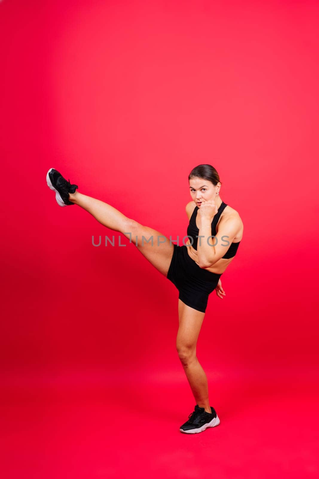 Cool female fighter in boxing bandages trains in a studio. Mixed martial arts.