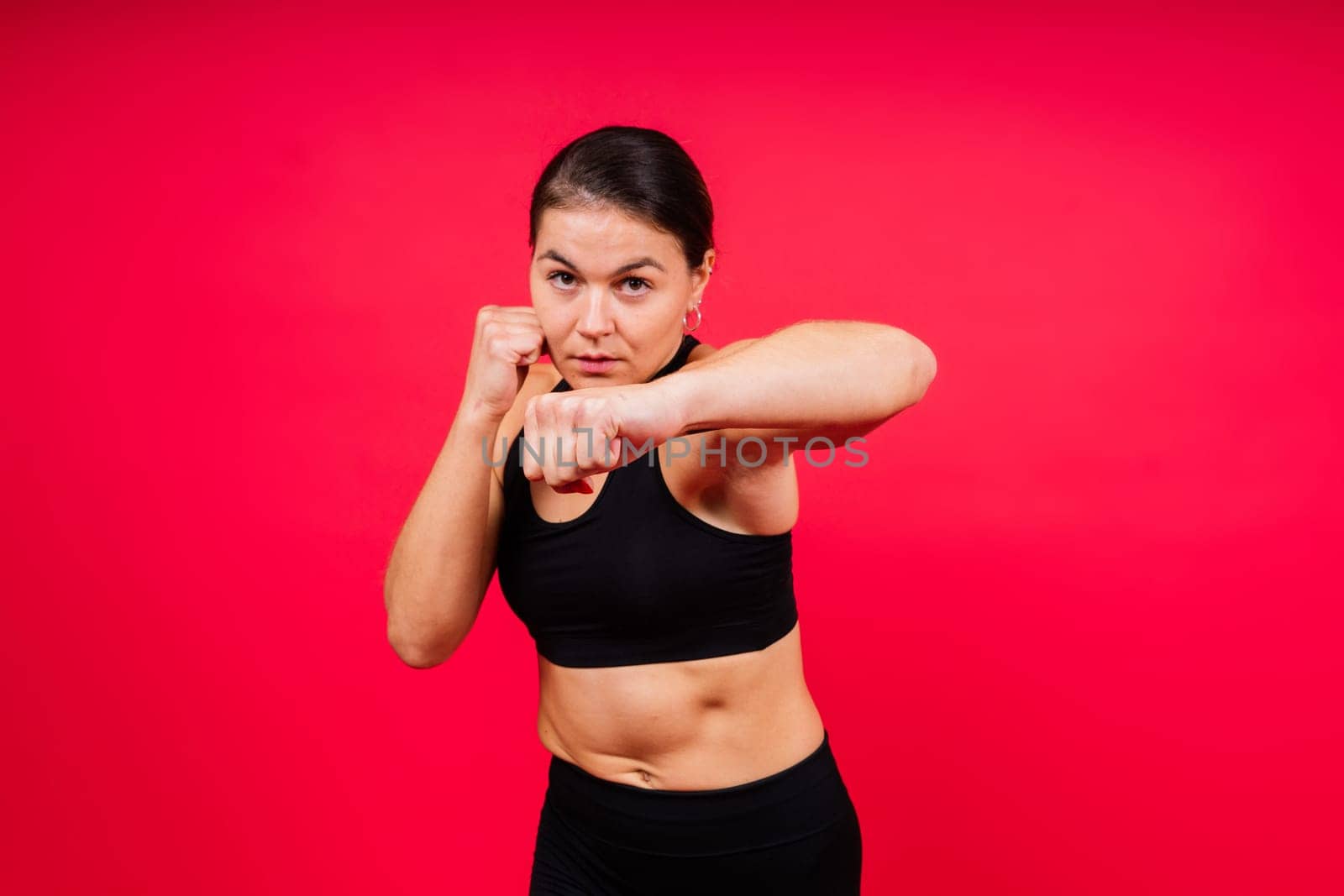 Cool female fighter in boxing bandages trains in a studio. Mixed martial arts.