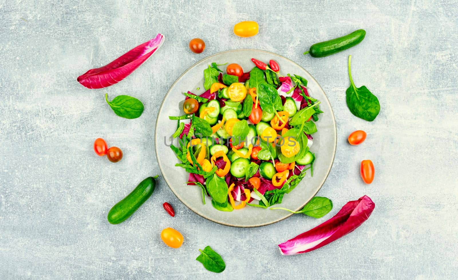 Summer natural salad of tomatoes, cucumbers, peppers and spinach. Vegetarian food