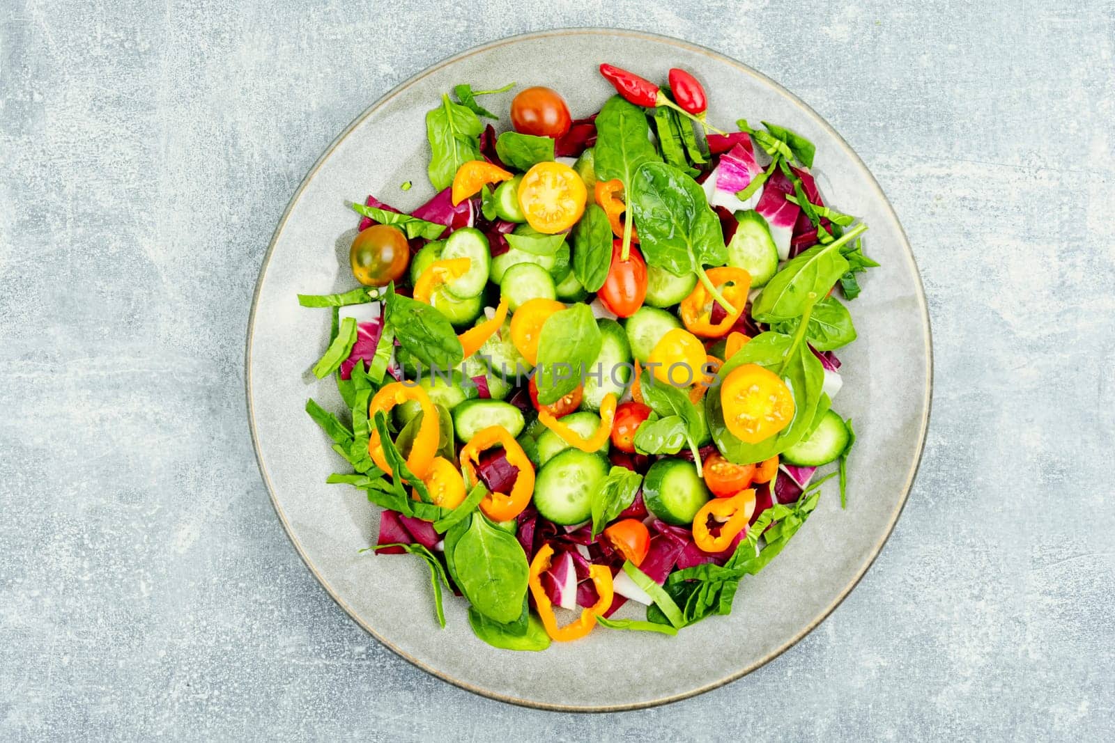 Summer natural salad of tomatoes, cucumbers, peppers and spinach.