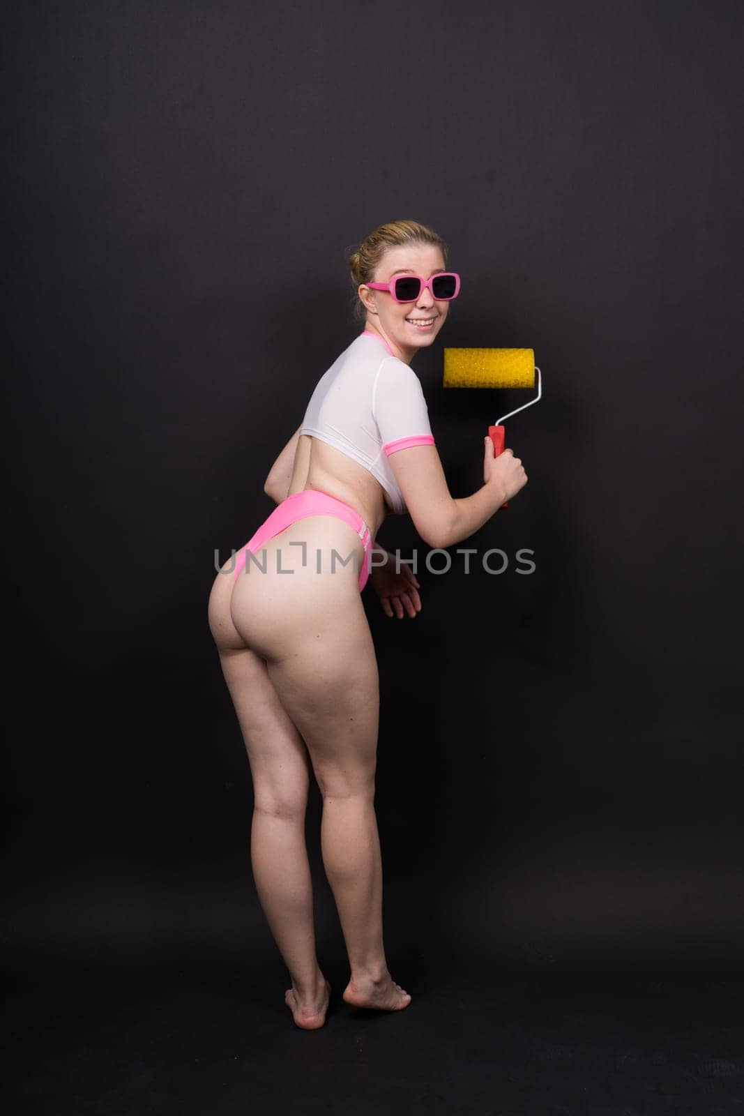 Young classic pin-up woman painting wall with a paint roller