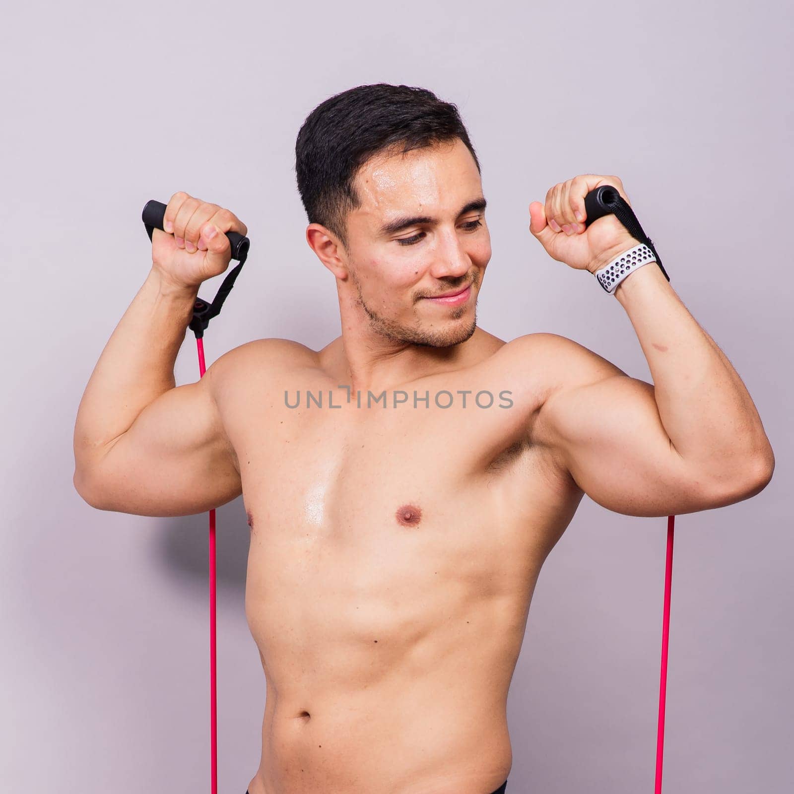 Athletic man skipping with jump rope on grey background. Best cardio workout