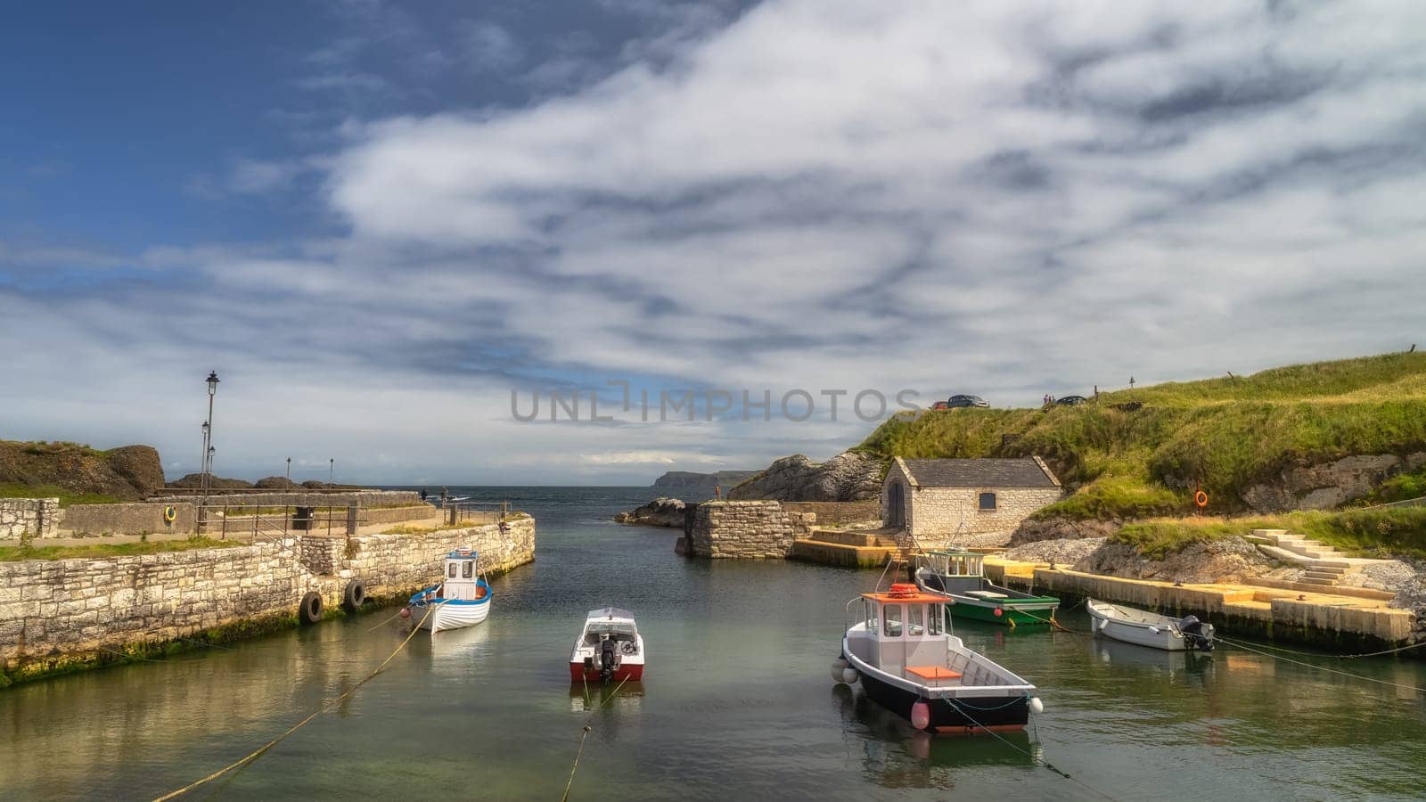 Beautiful small Ballintoy Harbour with stone pier and moored boats on Causeway Coast, County Antrim, Northern Ireland