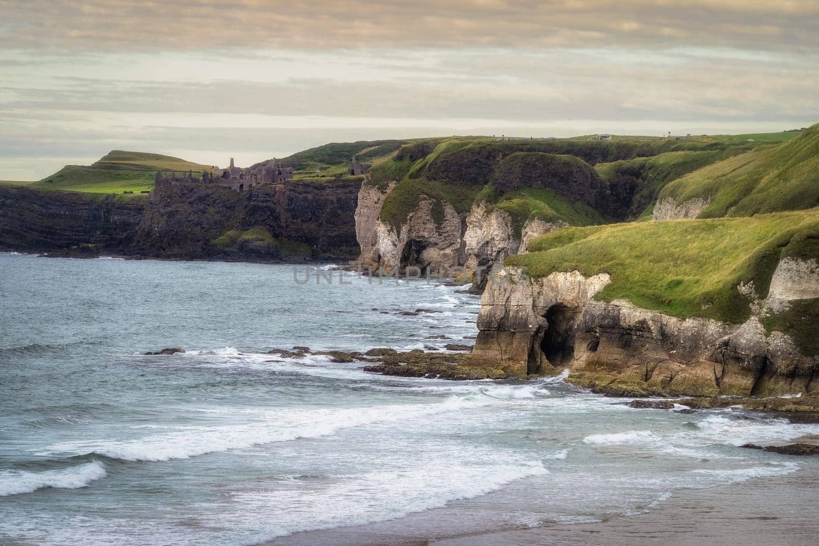 Dunluce Castle on the edge of cliff and limestone rock formations on White Rocks Beach, Causeway Coast, Wild Atlantic Way, Antrim, Northern Ireland