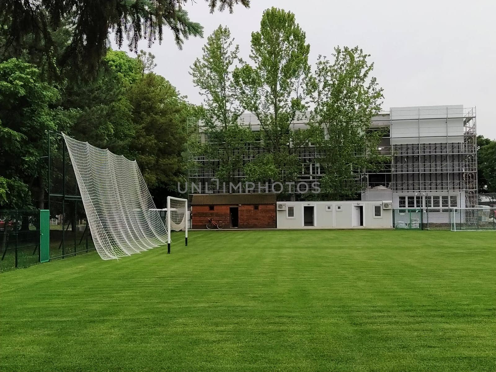 Sremska Mitrovica, Serbia. May 30, 2020. A football field on the school grounds and a football goal. The construction of a new school. School building in scaffolding. Facade work.