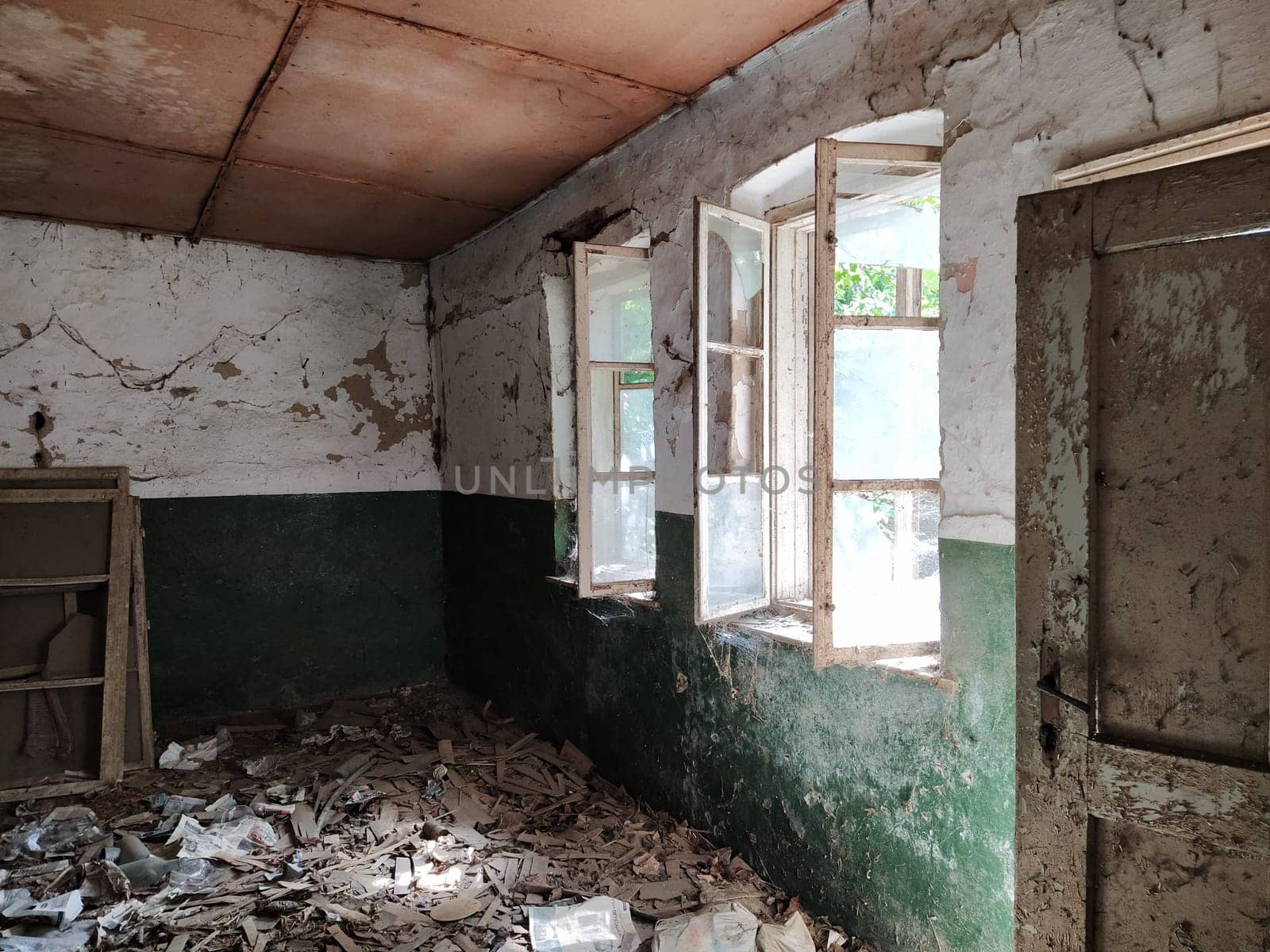 Scary windows. Inside an abandoned house. View of broken windows without a curtain. Grunge scene. Light shines through old wooden frames with broken glass. The concept of abandonment and uselessness