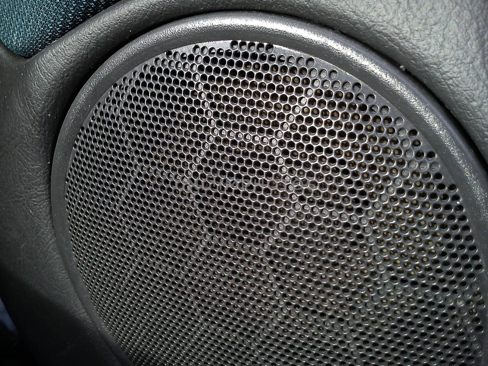 Gray grill from a music speaker in a car. The interior of the car. Acoustic stereo speakers. Radio in the form of toys or with a stylish design.