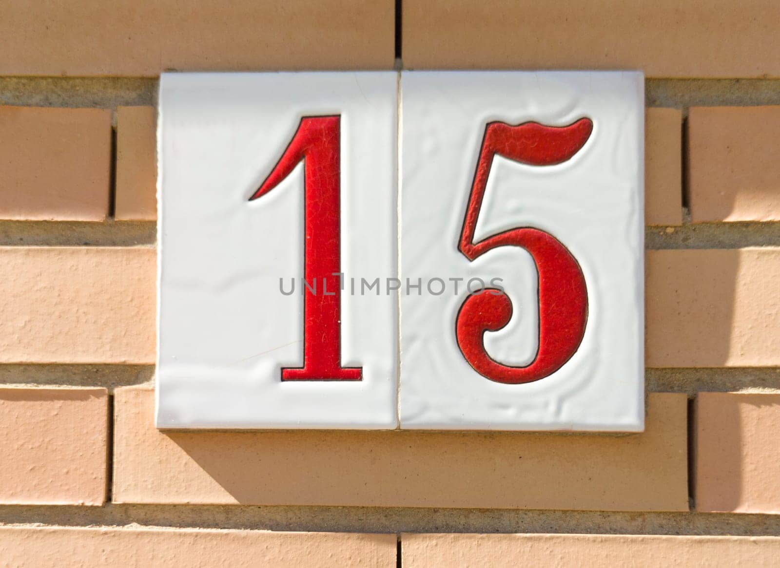House number 15 over brick sunny wall. Houses with personality concept