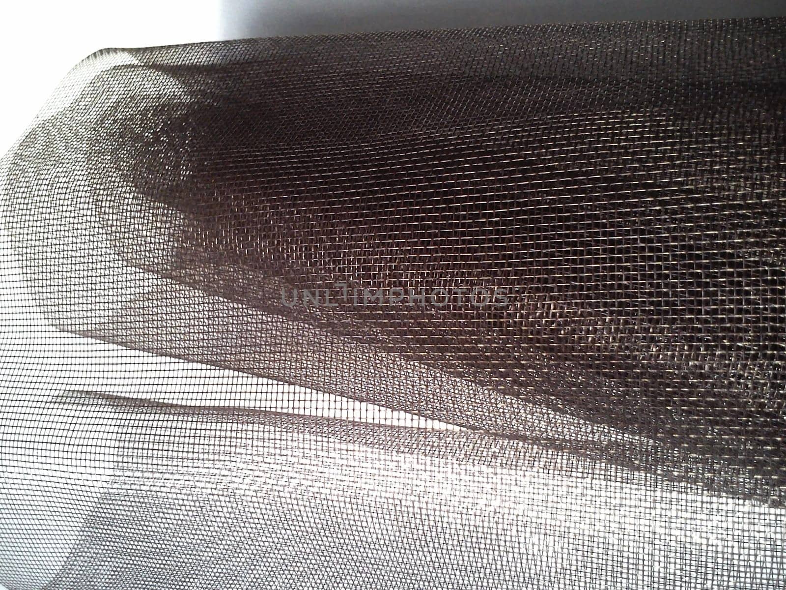 Mosquito net in a roll. Brown synthetic material on a white background. Weaving plastic threads. Convoluted lattice