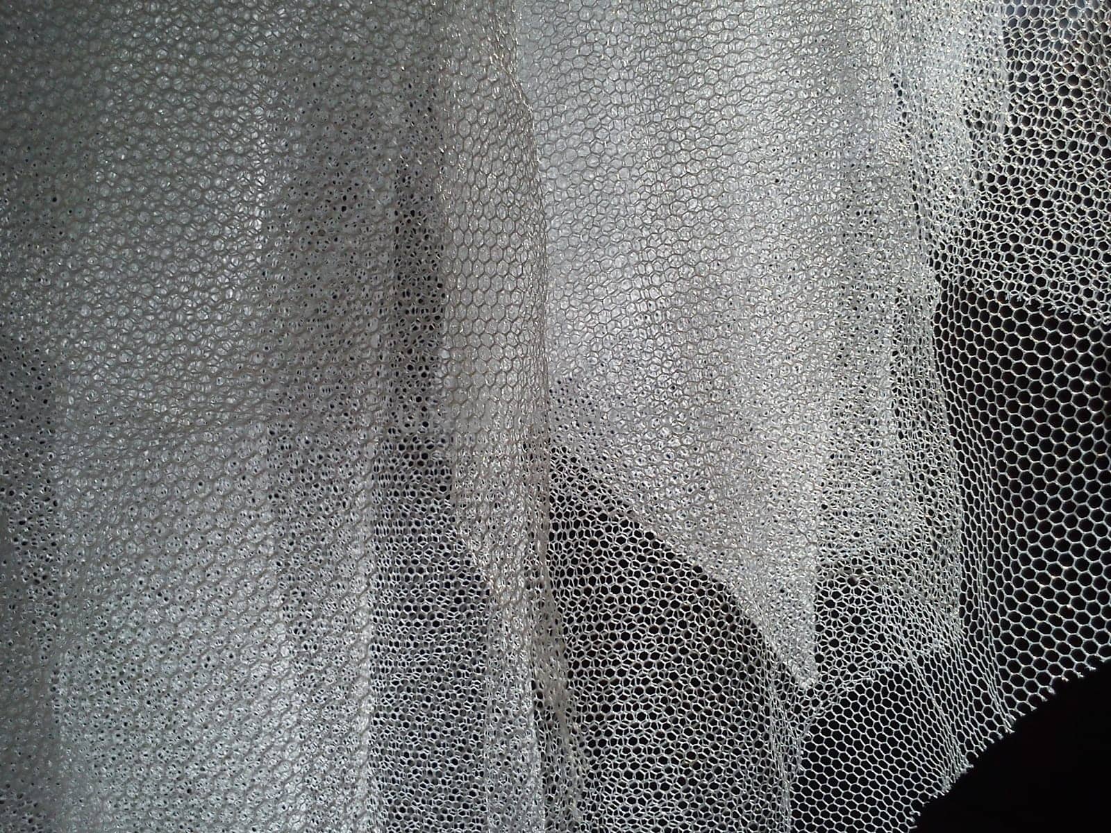 White wrinkled mesh fabric. A washable thing made of synthetic material. Mosquito net folded into soft folds. Fabric similar to a bridal veil.