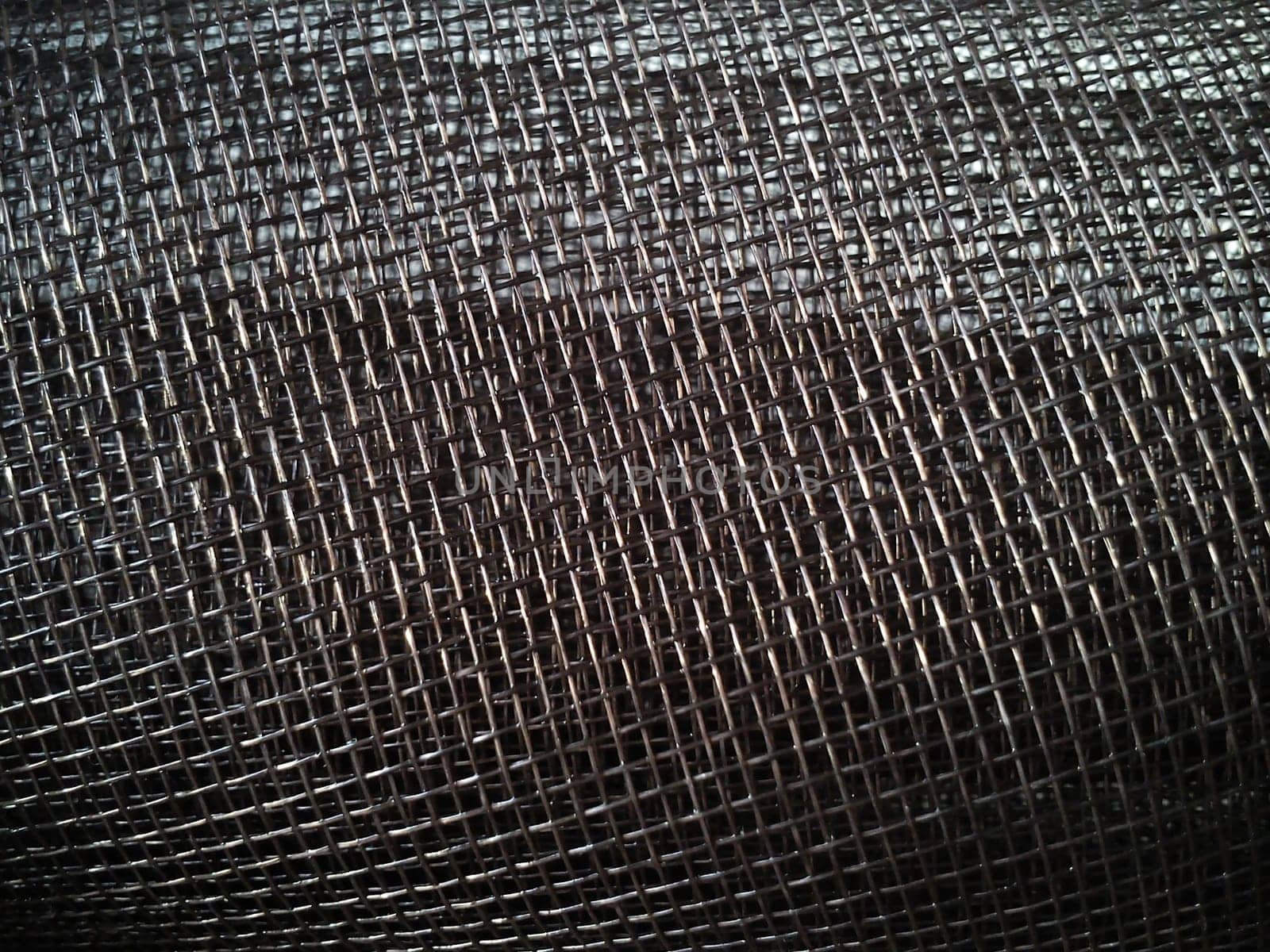 Mosquito net in a roll. Brown synthetic material on a white background. Weaving plastic threads. Convoluted lattice
