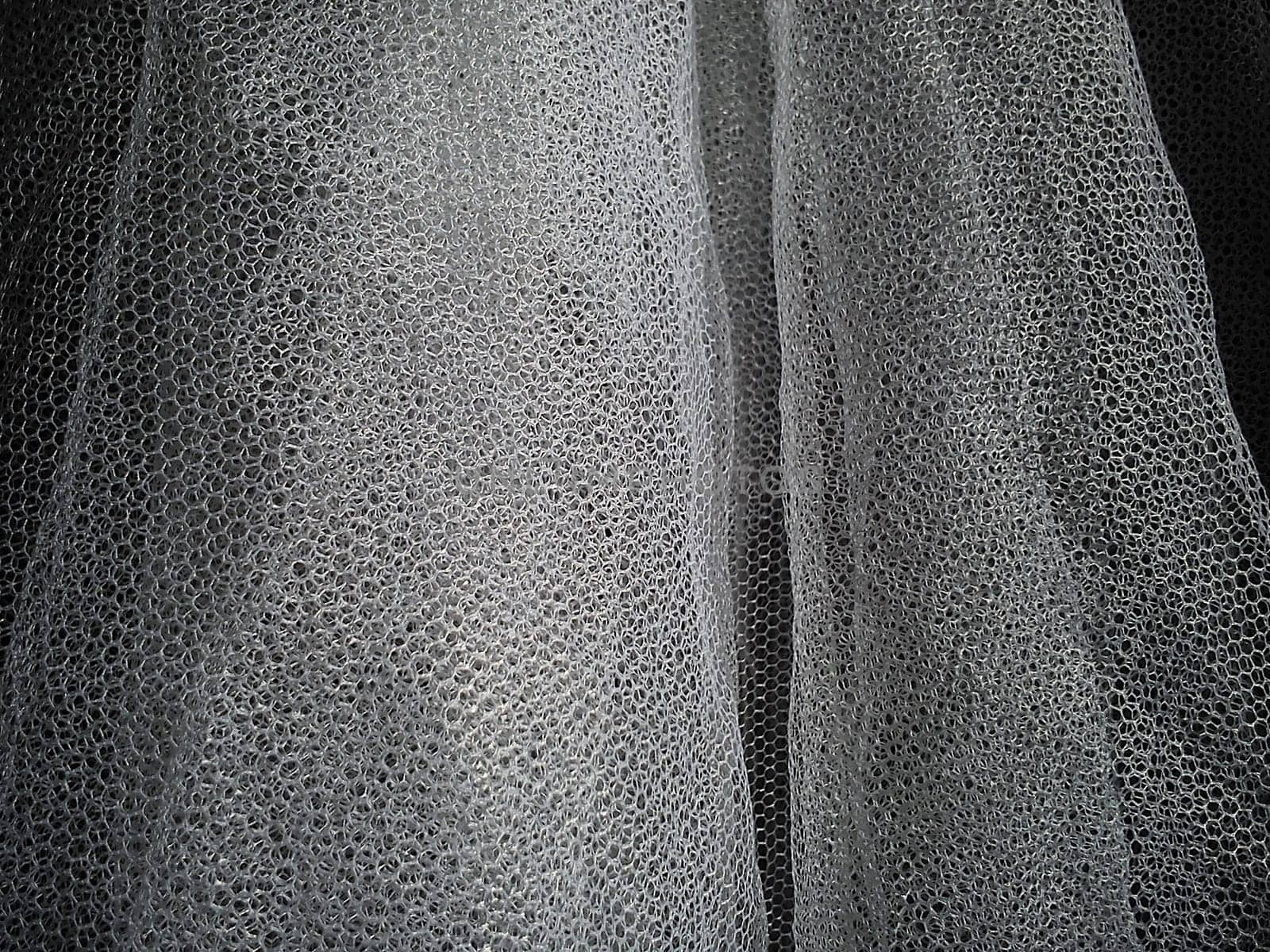 White wrinkled mesh fabric. A washable thing made of synthetic material. Mosquito net folded into soft folds. Fabric similar to a bridal veil.
