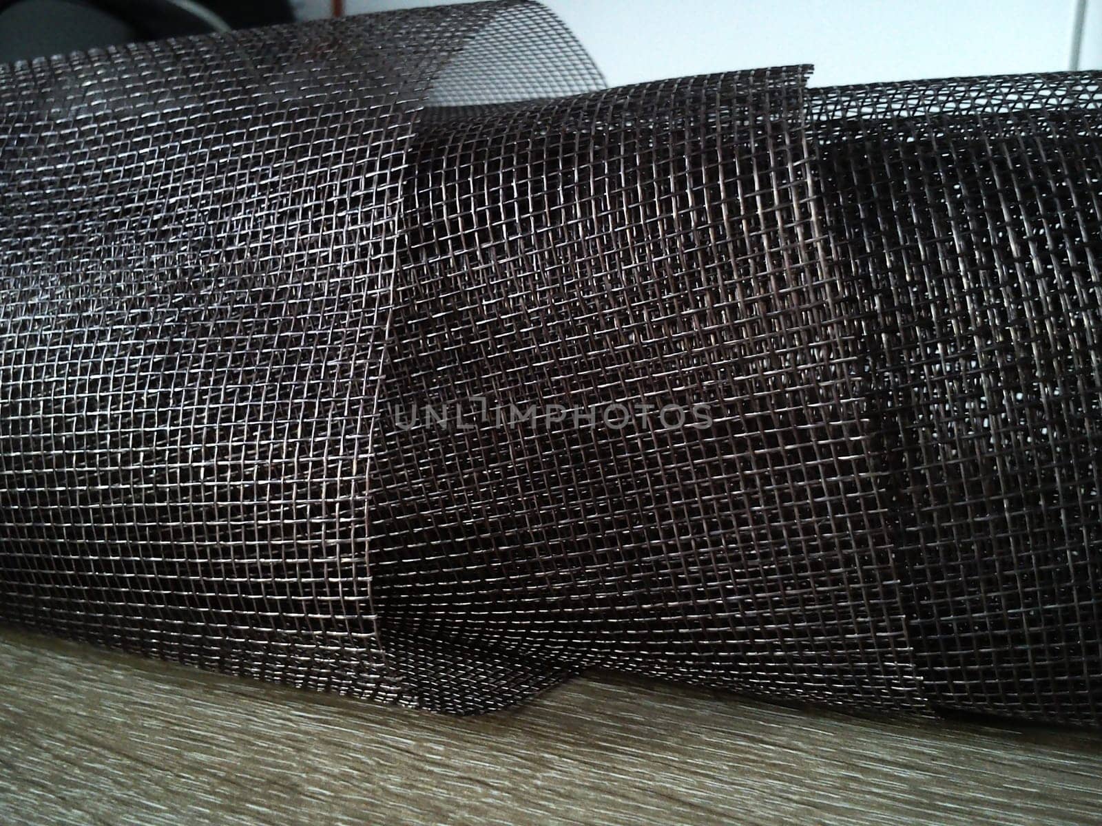Mosquito net in a roll. Brown synthetic material on a white background. Weaving plastic threads. Convoluted lattice