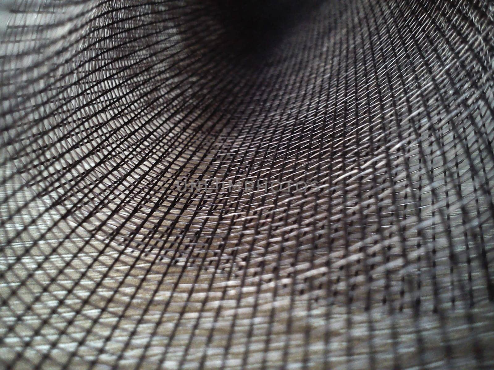 Mosquito net in a roll. Brown synthetic material on a white background. Weaving plastic threads. Convoluted lattice