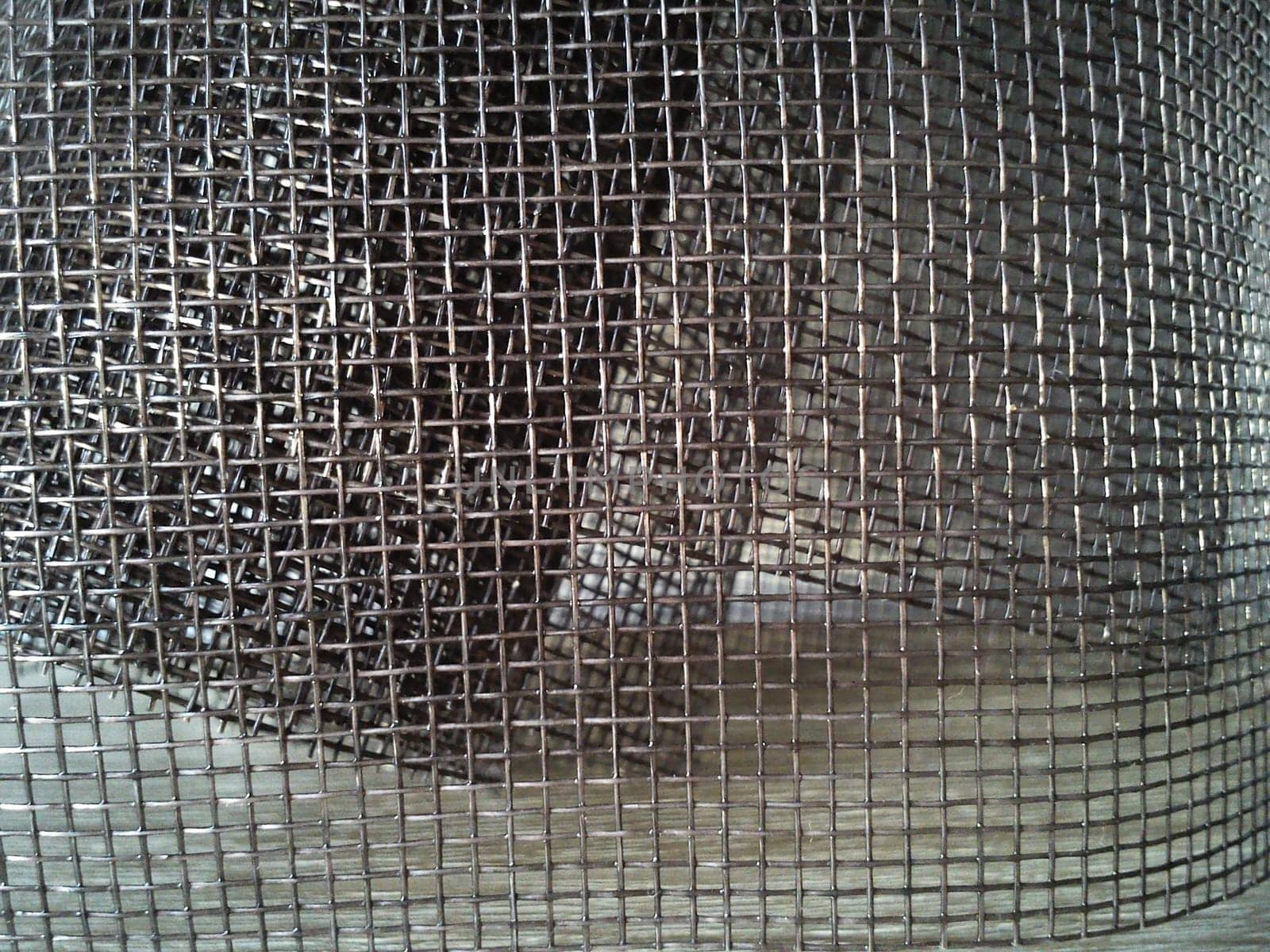 Mosquito net in a roll. Brown synthetic material on a white background. Weaving plastic threads. Convoluted lattice